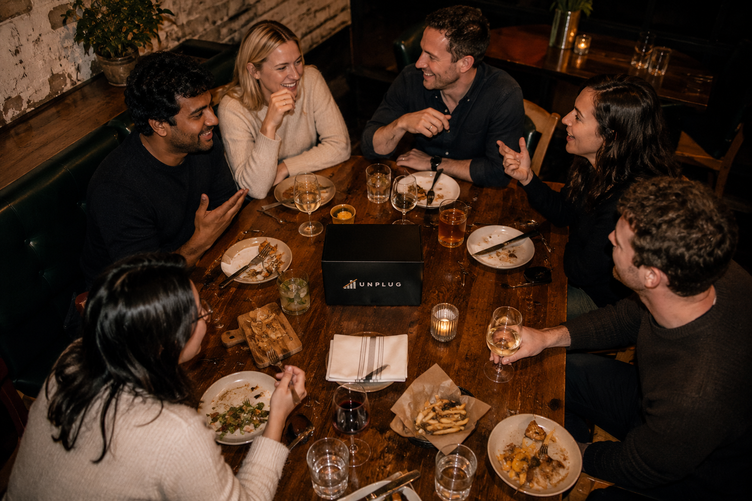 Group of six having dinner together, UNPLUG phone jail on the table